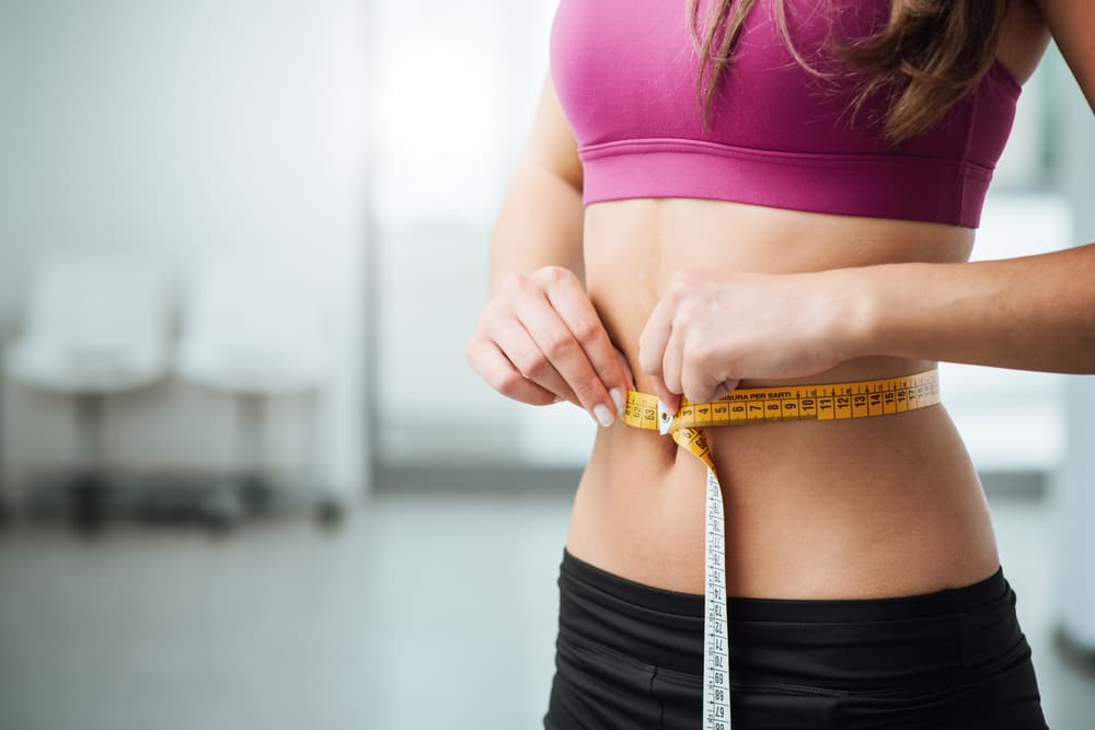 A patient measuring their waist during a body composition check