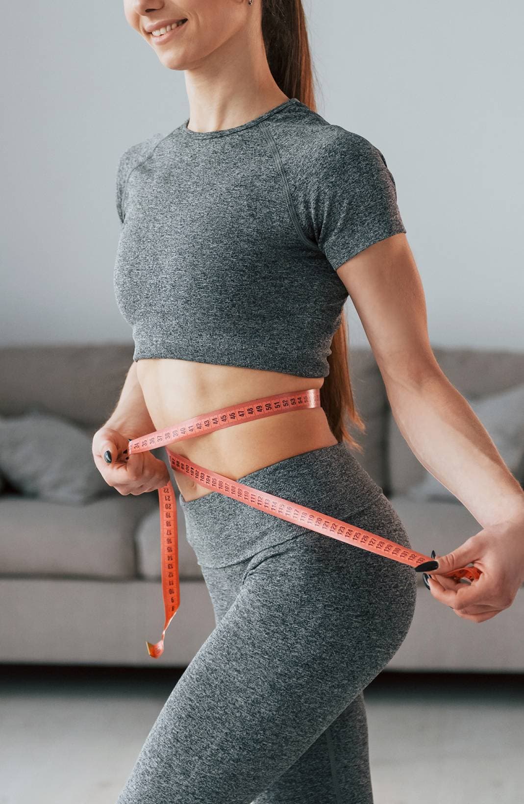 A woman measuring her waist to track metabolic progress